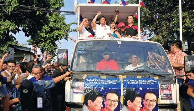A recent photo shows Philippine presidential candidate and mayor of Davao city, Rodrigo Duterte (second left) accompanied by his running mate senator Alan Peter Cayetano (right), raising his fist during their motorcade campaign in Cainta Rizal, east of Manila.