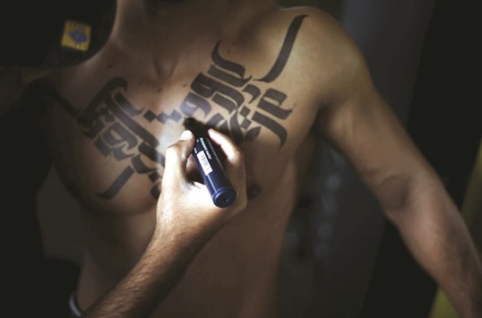 Palestinian artist Belal Khaled paints Arabic letters on a bodybuilder in a gym in Gaza City.