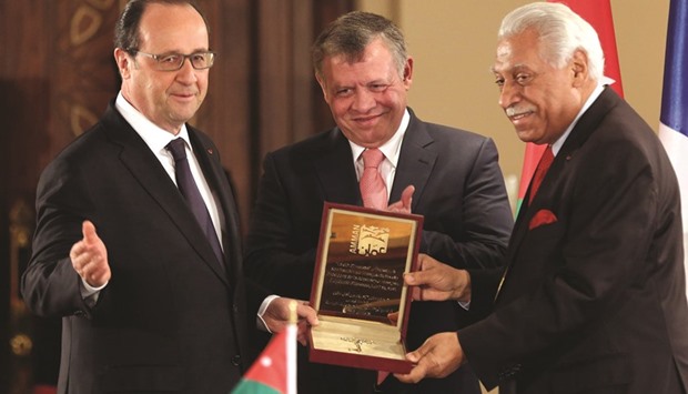 French President Francois Hollande receives a ceremonial key to the city of Amman from mayor Aqel Biltaji (right) as Jordanian King Abdullah II looks on during a meeting in Amman yesterday.