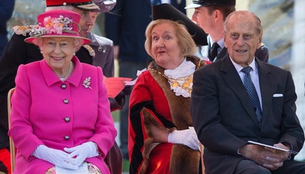 Queen Elizabeth II smiles as she sits with her husband Prince Philip, Duke of Edinburgh and the Mayor of Windsor, Eileen 'Dee' Quick, during the opening of a bandstand at Alexandra Gardens in Windsor, west of London, on Wednesday, the day before her 90th birthday.