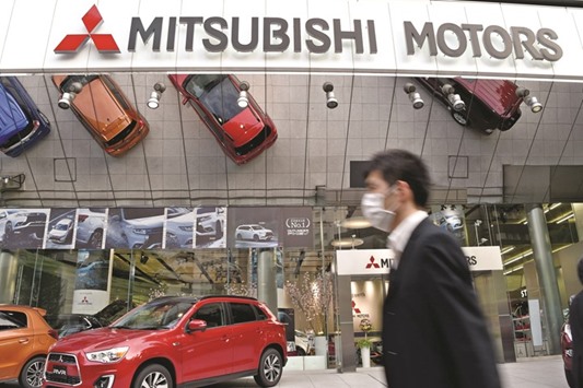 A businessman walks past the Mitsubishi Motors headquarters in Tokyo. Shares in the Japanese automaker yesterday plunged to u00a5583 ($5.31), down 20%, after diving 15% on Wednesday when news of the fuel-cheating first broke.