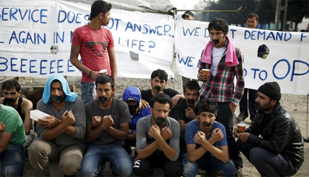 Migrants and refugees with their mouths taped stage a protest at Greek-Macedonian border