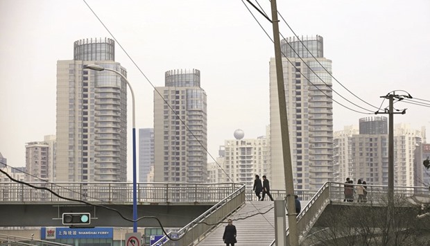 People walk on a bridge near the financial district of Pudong in Shanghai. While property prices in top-tier Chinese cities are booming, prices in smaller cities, where most of its urban population lives, are still sinking, complicating government efforts to spread wealth more evenly and arrest slowing economic growth.