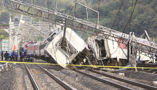 South Korea railway workers are seen with the derailed passenger train near the southern port city of Yeosu.