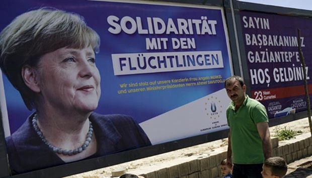 People walk past a banner with a picture of German Chancellor Angela Merkel on a main street in Gaziantep, Turkey, on Saturday. The banner in German reads, ,Solidarity with refugees. We are proud of our Chancellor Angela Merkel and Prime Minister Ahmet Davutoglu,.