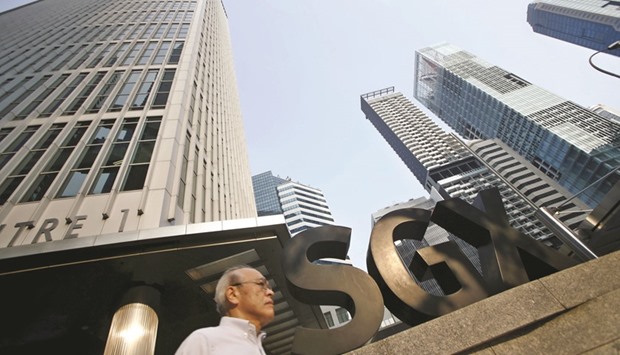 A man passes the SGX building in Singaporeu2019s central business district. The Monetary Authority of Singapore and the Commercial Affairs Department are investigating possible contraventions of the Securities and Futures Act and have obtained documents from several broking firms and trading representatives, the MAS said on Friday.