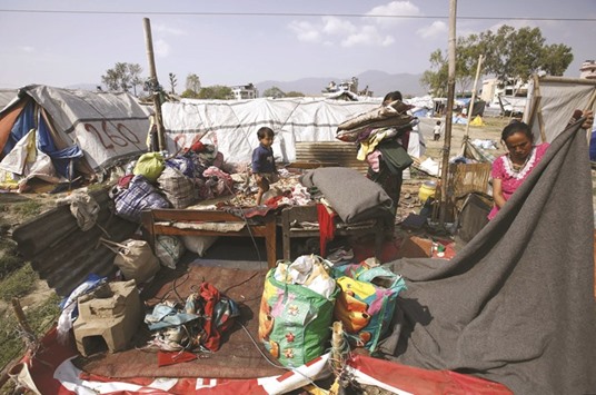 Kumari Kaflay, right, from Sindhupalchok district, arranges her belongings after a windstorm destroyed her temporary shelter at a camp where families displaced by the April 2015 earthquake live in Kathmandu.