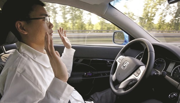 A development engineer at Changan Automobile lifts his hands off the steering wheel as the car is on self-driving mode during a test drive on a highway in Beijing.