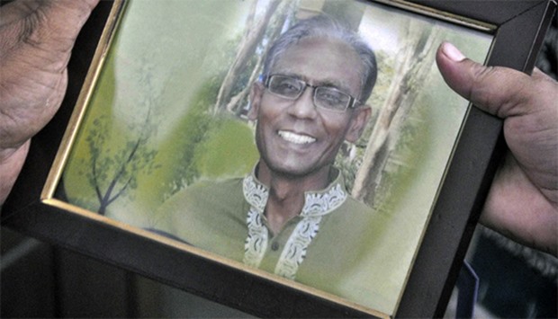 A man holds a portrait of Bangladeshi professor Rezaul Karim Siddique