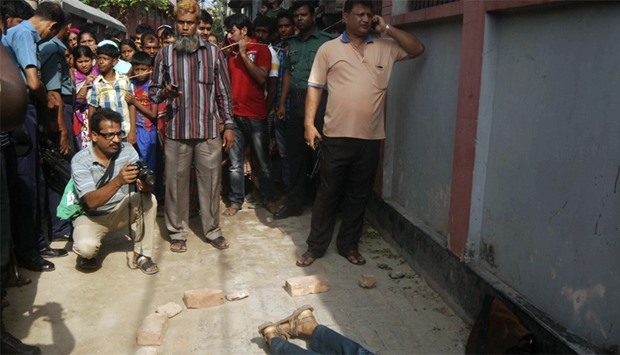 People gather around the body of Bangladeshi professor Rezaul Karim Siddique after he was hacked to 