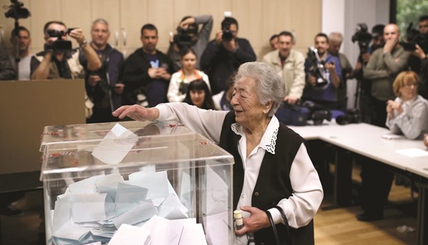 An elderly woman casts her vote under the media glare at a polling station in Belgrade.