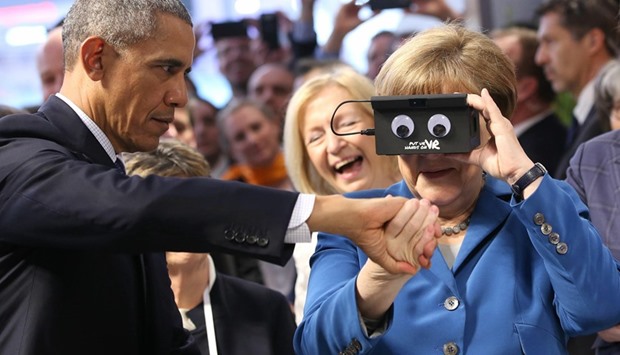 German Chancellor Angela Merkel looks through a u2018virtual realityu2019 device next to US President Barack Obama at the Hanover Industrial Fair.