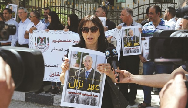Palestinian journalists hold placards and banners during a demonstration on Sunday, outside the Red Cross offices in the West Bank city of Ramallah, in support of their colleague, Omar Nazzal, who was detained the previous day by Israeli forces.