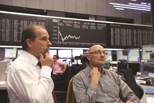 Traders sit in front of the German share price index board at the Frankfurt Stock Exchange. The DAX 30 closed down 0.3% to 10,259.59 points yesterday.