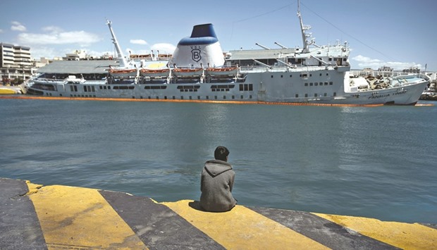 A migrant looks yesterday at the listing decommissioned passenger ferry Panagia Tinou, at the port of Piraeus, near Athens.