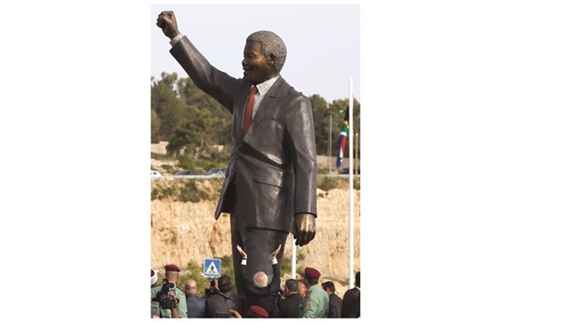 Palestinian and South African officials stand next to a giant statue of Nelson Mandela during its inauguration ceremony in the West Bank city of Ramallah yesterday.