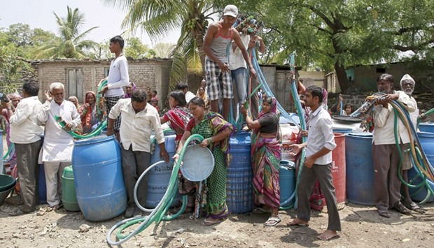 Residents hold plastic hoses as they wait for the government-run water tanker in Masurdi village, in Latur, Maharashtra. The state is in the grip of a severe drought.