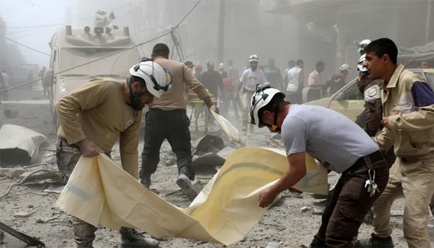 Syrian civil defence volunteers arrive to wrap a body in a plastic bag following a reported air stri
