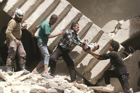 Syrian civil defence volunteers and rescuers remove a baby from under the rubble of a destroyed building following a reported air strike on the rebel-held neighbourhood of Al Kalasa in the northern Syrian city of Aleppo.