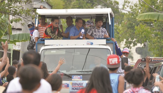 Boxing legend Manny Pacquiao (top right) and Presidential candidate Vice-President Jejomar Binay (centre) throw T-shirts to supporters during a campaign sortie in Calamba town, Laguna province, south of Manila.