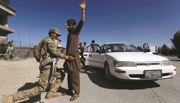 An Afghan policeman inspects passengers at a checkpoint on the outskirts of Jalalabad province yesterday.