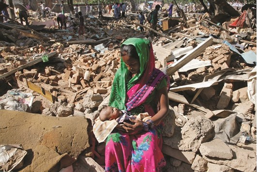 A woman cradles her baby after her house was demolished by local authorities at a slum area in Chandigarh yesterday.