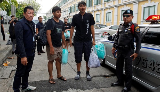 Police officers escort three of the eight people charged with sedition and computer crimes as they arrive at the military court in Bangkok yesterday.