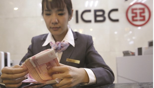 A clerk of ICBC counts one hundred yuan banknotes at a branch in Beijing.  The bank avoided posting a quarterly drop in profit after letting its buffer for covering bad loans fall below a regulatory minimum.