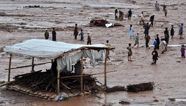 Flood waters rush through a Pakistani market area as vendors and residents scramble to save their possessions on the outskirts of Peshawar on Sunday.