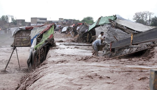 Men collect their belongings from their makshift shop which was damaged by flood water after heavy rain on the outskirts of Peshawar.