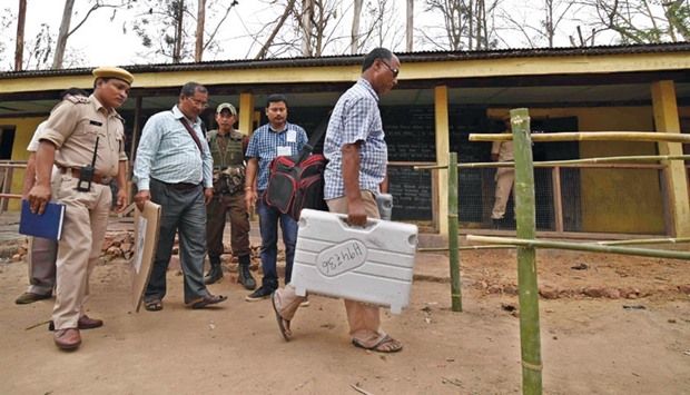 A polling officer carries an electronic voting machine and election material into a polling booth on the eve of Assam assembly elections in Diphu in Karbi Anglong district, some 215km from Guwahati yesterday.