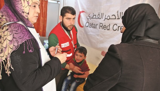 A QRCS official administers a vaccination to a Syrian child.