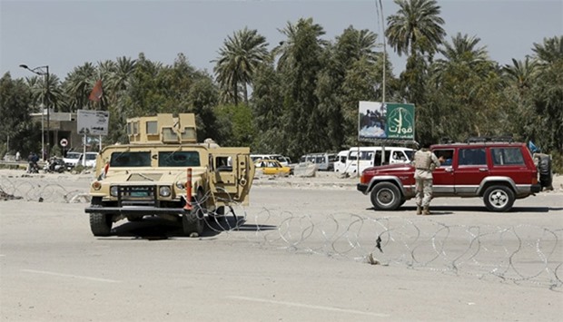 Iraqi security forces stand guard near the site of a suicide attack