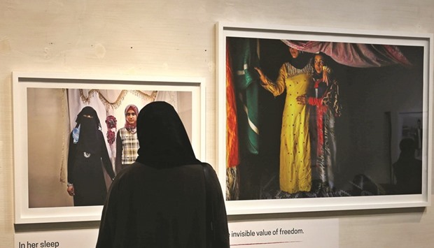 A woman looks at images taken by Jordanian photographer Tanya Habjouqa of Syrian refugees during a joint exhibition along with Syrian artist Omar Imam on refugees and migrants fleeing war and poverty, on March 10, 2016 in Dubai. The exhibition also pays tribute to photographer Leila Alaoui, who was among dozens killed in a January attack claimed by Al Qaeda on a hotel in Burkina Faso.