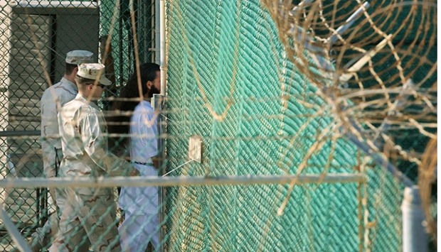 US military guards moving a detainee to an undefined facility inside Camp Delta in the Detention Center at Guantanamo Bay, Cuba, on March 29, 2010.