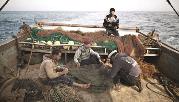 Gaza fishermen fix the nets on a boat belonging to the Abu Ouda family as they start fishing off the coast of the Gaza Strip on Sunday. Gaza fishermen have begun working further off the coast after Israel relaxed restrictions for the first time in a decade but said that the measure was not nearly enough.