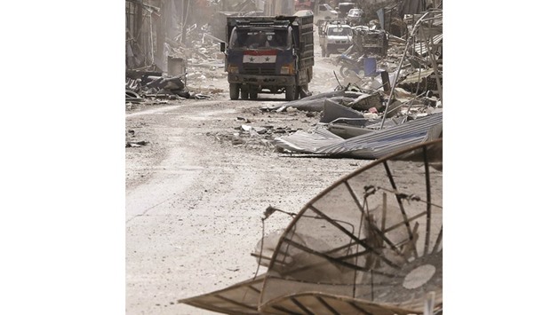 A truck adorned with the Syrian flag drives amidst destruction in the town of Al-Qaryatain, in the province of Homs in central Syria, yesterday after Syrian troops regained control of the town from the Islamic State group the previous day.