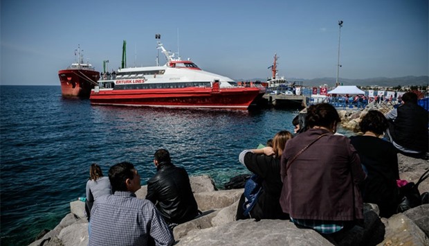 People gather on the beach as migrants deported from Greece arrive aboard a small Turkish ferry in the port of Dikili district in Izmir, Turkey.