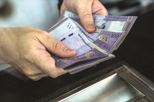 An employee counts Malaysian ringgit banknotes at a currency exchange store in Kuala Lumpur. The currency posted its biggest gain since 1973 in the first quarter and this yearu2019s 9.5% advance is the biggest in Asia.