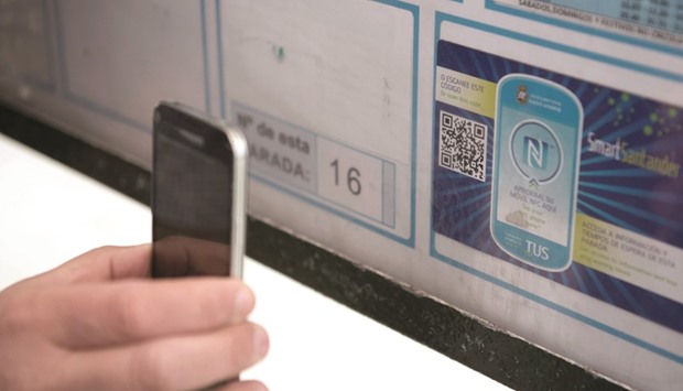 A person using a mobile phone to read a QR code or u201csmart stickeru201d on a public bus stop in  Santander. The QR codes or u201csmart stickeru201d on public bus stops are used to know the bus schedules and information about different bus lines.