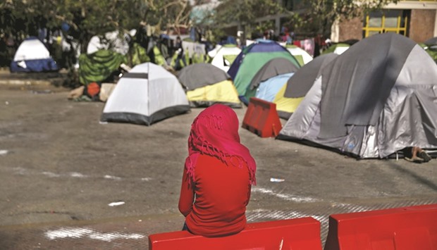 A girl sits near tents at a makeshift camp for refugees and migrants at the port of Piraeus, near Athens.