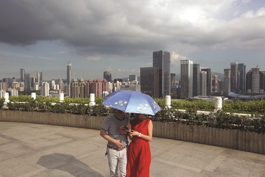 Visitors walk at a park overlooking the city of Shenzhen. After Shenzhen and Shanghai property prices had jumped 57% and 20.6% in February from a year earlier, local governments tightened downpayment requirements for second homes and raised the eligibility bar for non-residents to buy in the cities.