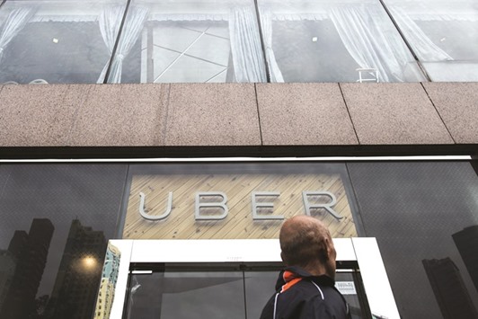 A pedestrian walks past an Uber Technologies office during a driver recruitment event in Hong Kong. Uber drivers suing to be treated like employees are trying to add $1bn in penalties under Californiau2019s unique u201cbounty hunteru201d statute as they prepare for trial in June.