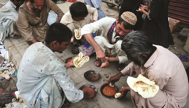 Pakistani residents eat food given out by a charity outside a restaurant in Karachi yesterday.