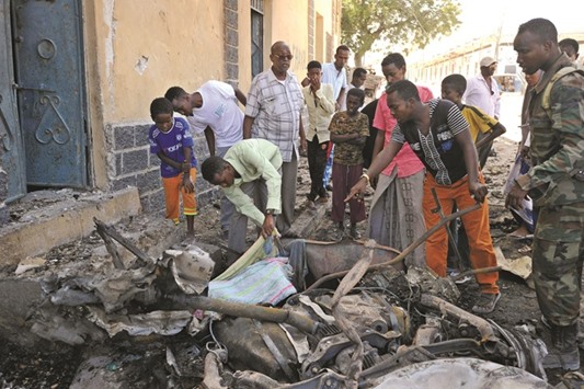 People stand around the debris at the site of a car bomb blast outside a Mogadishu restaurant.