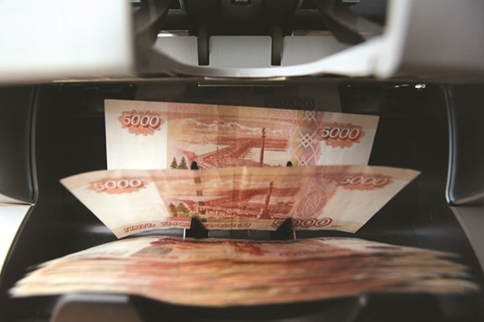 Russian rouble banknotes pass through a money counting machine at a store in Moscow. A weaker rouble is better for growth in the view of more than half the 19 analysts in a Bloomberg survey.