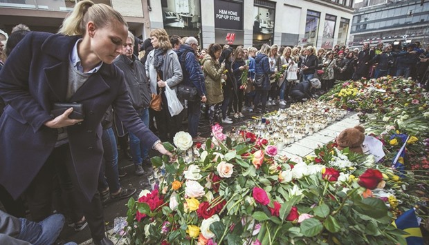 A woman lays flowers to commemorate the victims of Fridayu2019s terror attack at a makeshift memorial near the site where a truck drove into Ahlens department store.