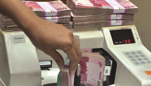 An employee counts Indonesian rupiah banknotes at a money changeru2019s office in Jakarta. The rupiah may slump 1.7% by the end of June, the median of analystsu2019 estimates compiled by Bloomberg shows.