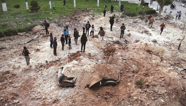 Syrians gather at the site following an air strike on the northern city of Idlib yesterday.