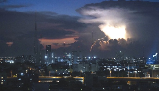 An electrical storm passes as the sun sets in Bangkok yesterday.